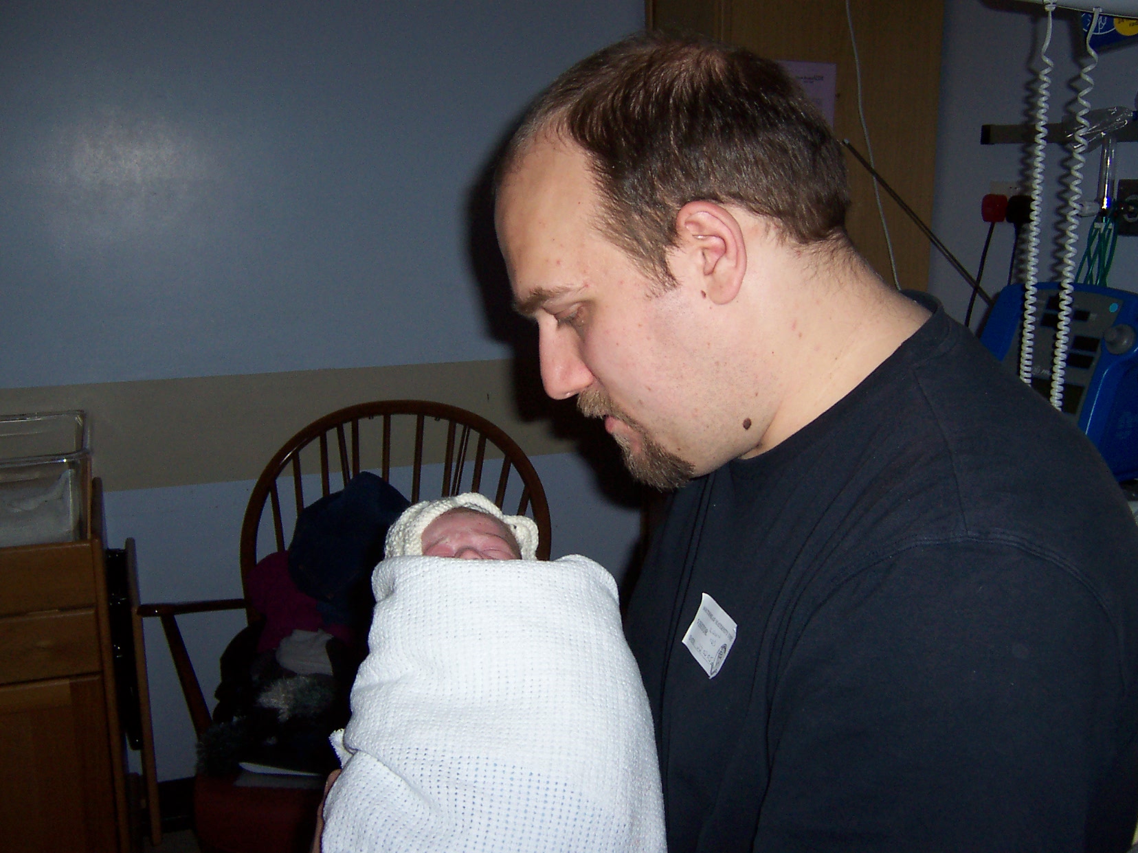 Photo of dad and baby just after birth. Dad is looking with awe at his new baby